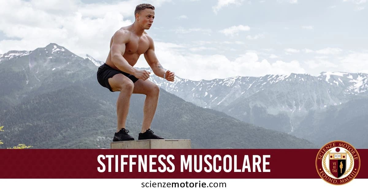 Persona che esegue un esercizio fisico all'aperto su una piattaforma con montagne innevate sullo sfondo, a torso nudo e in pantaloncini.In basso a destra è presente il logo di ScienzeMotorie.com