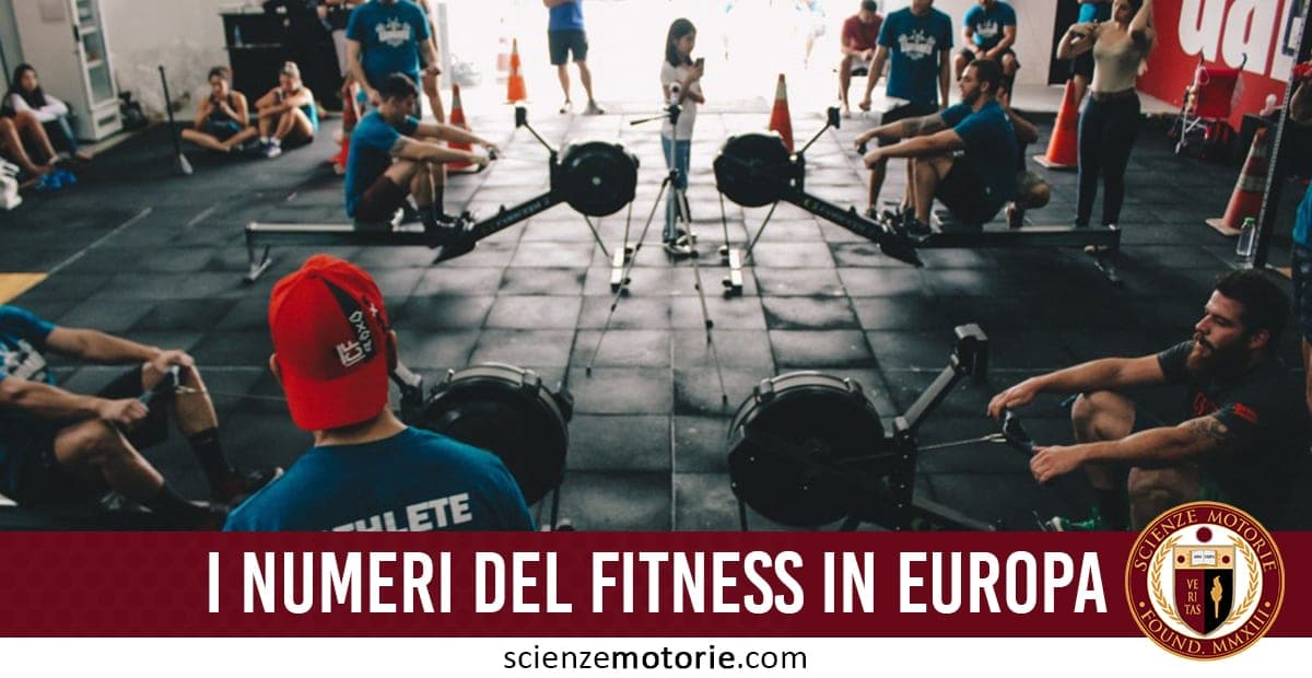 Immagine di un allenamento collettivo in palestra con persone su vogatori sincronizzati. Alcuni indossano magliette blu, altri osservano o supervisionano. In primo piano, una persona con cappello rosso. Sullo sfondo, un tipico centro fitness indoor. In basso, una fascia rossa con la scritta "I NUMERI DEL FITNESS IN EUROPA", e il logo di ScienzeMotorie.com