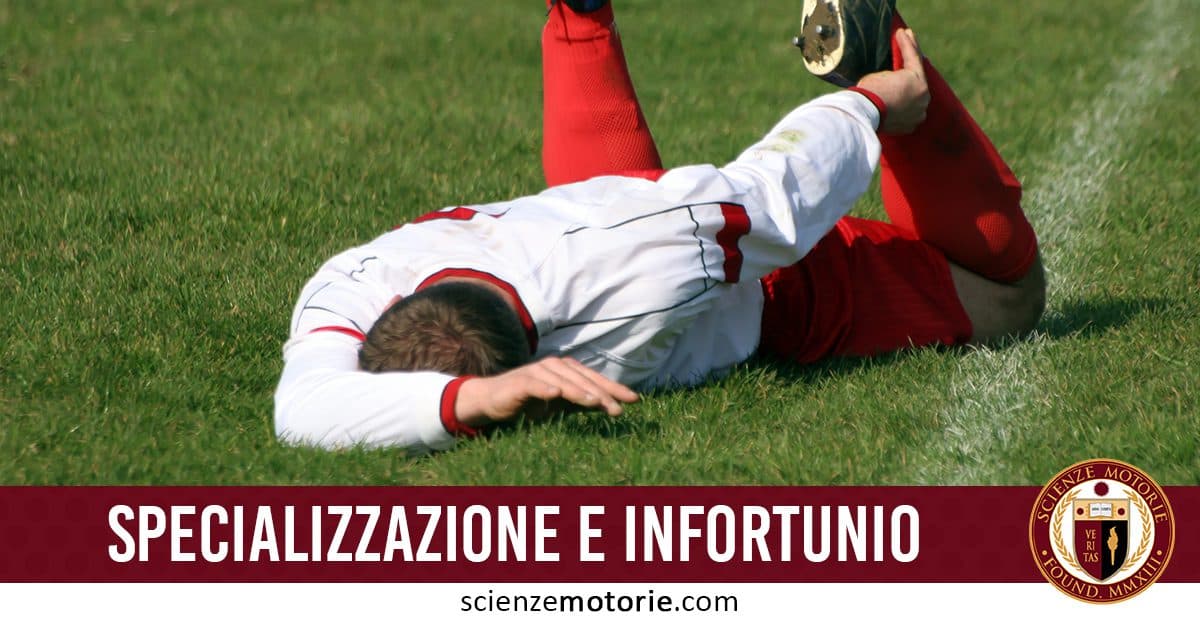 Giocatore di calcio a terra sul campo d’erba, infortunato, con maglia bianca e dettagli rossi.